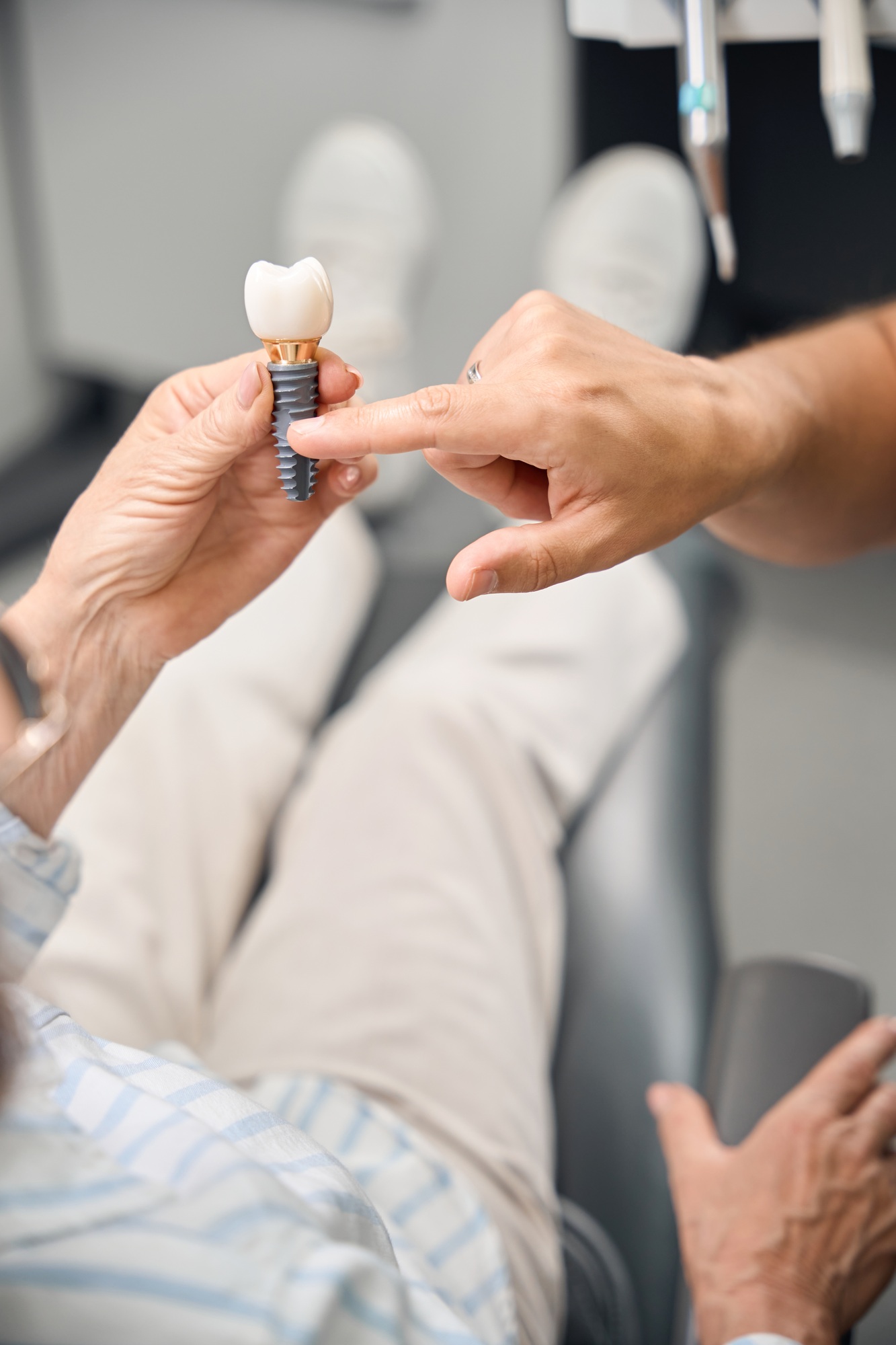 Female holds model of dental implant in hands